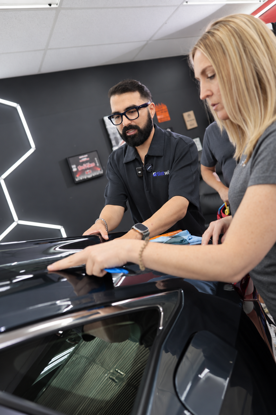 Marco Cazorla coaching a student as she positions window film on a car